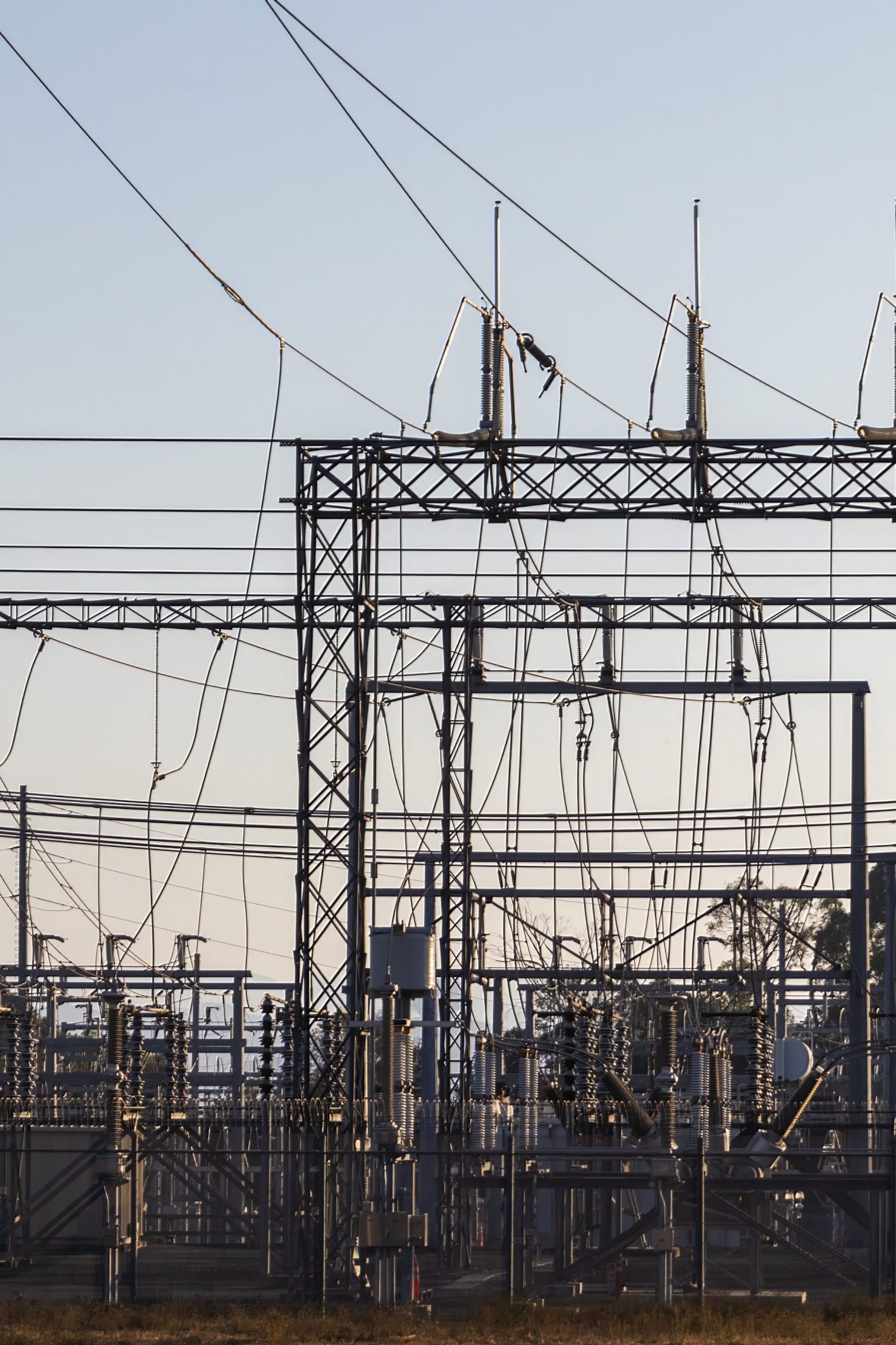 High-voltage electrical substation with steel structures and power lines at dawn.