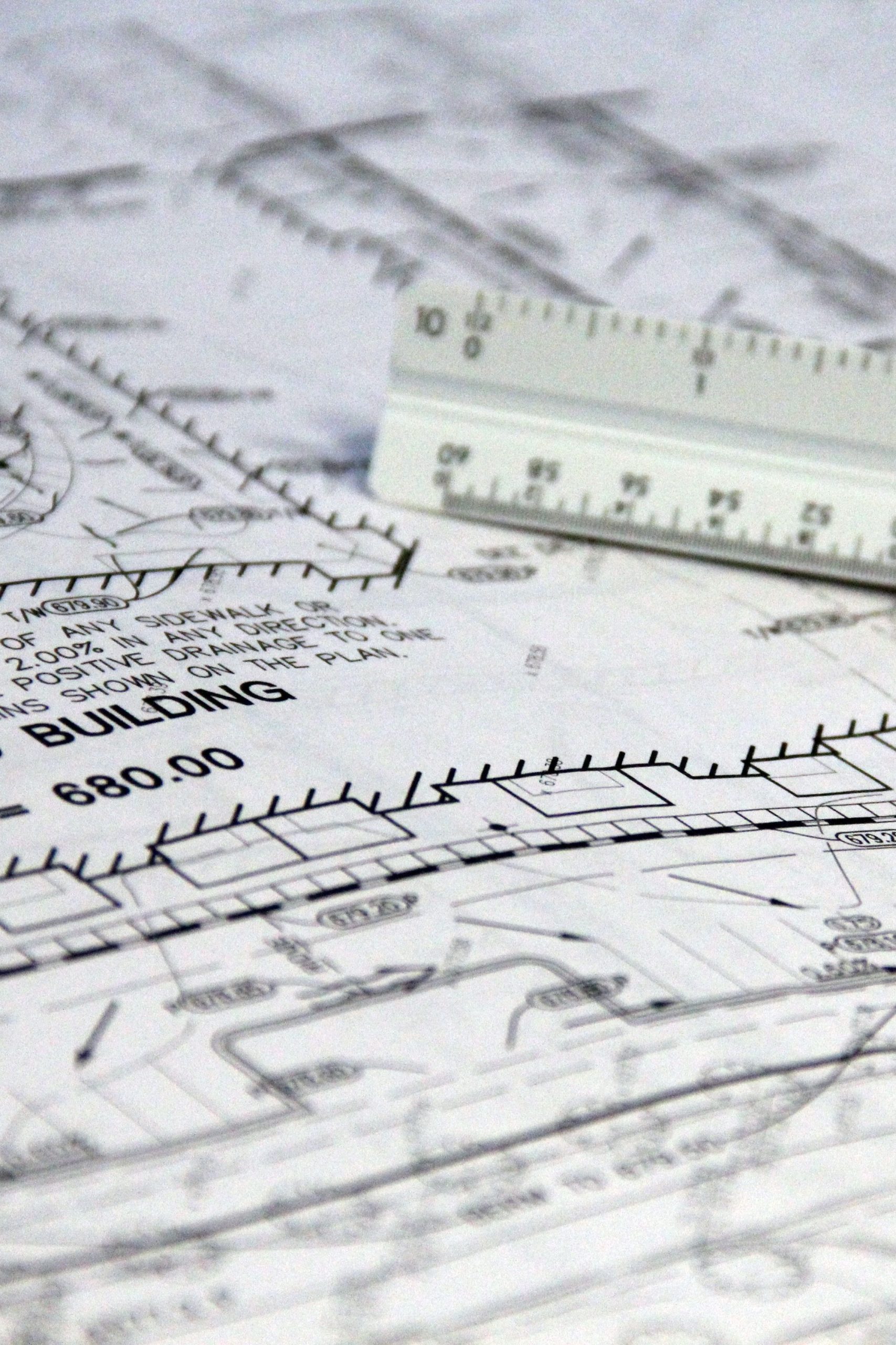 Detailed close-up of architectural blueprints with scale ruler, showing building plans and measurements.